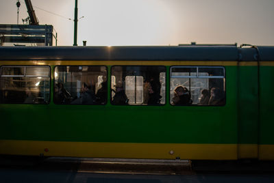 Train moving in city on sunny day against sky