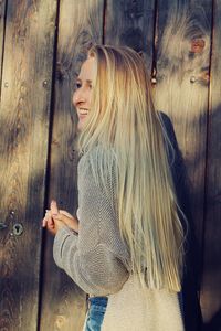 Side view of a young woman standing on wood
