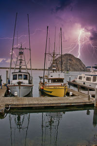 Sailboats moored at harbor against sky