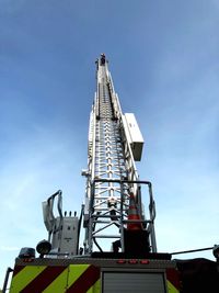 Low angle view of crane by building against sky