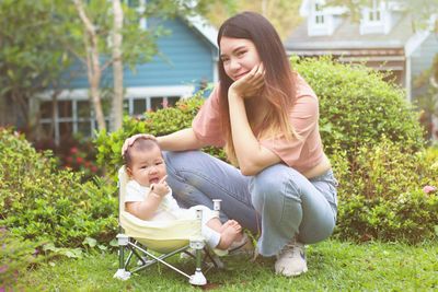 Happy young woman with baby sitting on plants