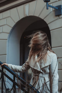 Rear view of woman against railing. wind blowing hair