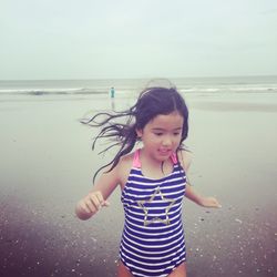 Cute girl walking at beach against sky