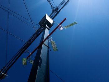 Low angle view of telephone pole against clear blue sky