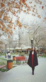 Full length of woman with umbrella against trees