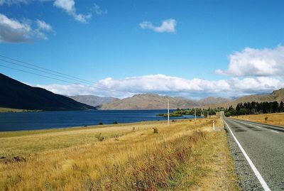 Scenic view of road by mountains against sky