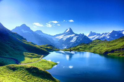 Scenic view of lake and mountains against blue sky