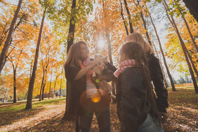 Low section of woman standing by trees in forest during autumn