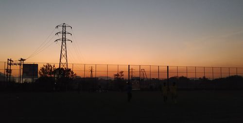 Silhouette cranes against sky during sunset