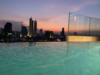 View of swimming pool against buildings at sunset