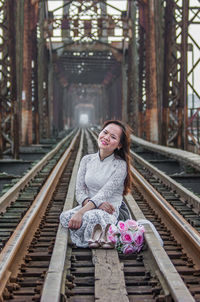 Portrait of woman sitting on railroad track