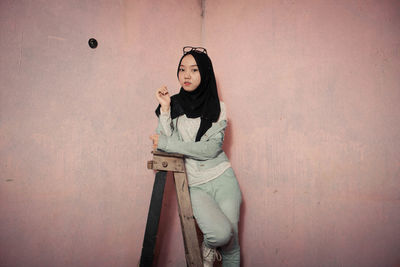 Portrait of woman standing against wall