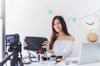 Portrait of young woman using phone while sitting on table