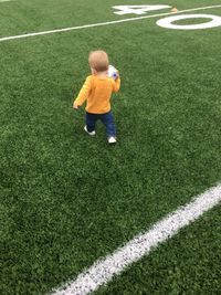 Rear view of baby boy walking on soccer field