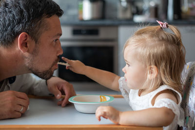 Cute daughter feeding father at home