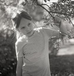Portrait of girl standing by tree