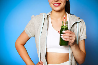 Midsection of woman holding while standing against blue background