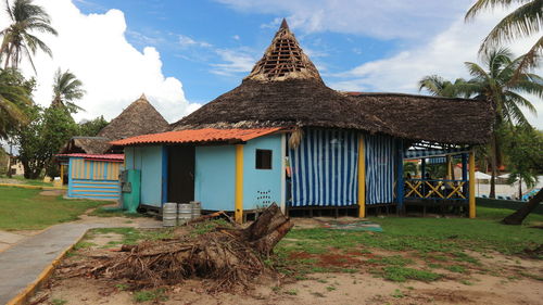 House by palm trees and houses against sky