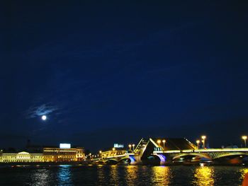 Illuminated bridge over river at night