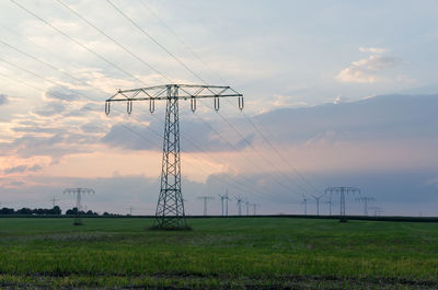 Electricity pylon on field against sky during sunset