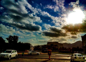 Cars on road against cloudy sky