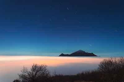 Mountain above the clouds at night against the starry sky
