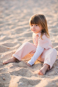 Pretty little child 2-3 year old playing at beach over sea at background in sun light outdoors.