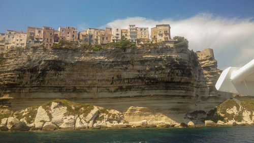 Buildings by sea against sky