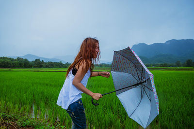 Smiling woman with umbrella standing on field