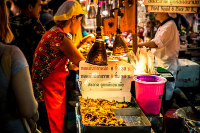 Side view of female vendor selling food at night market