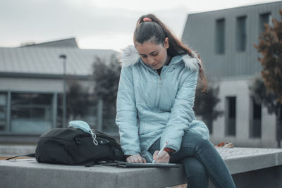 Young woman studying while sitting on bench