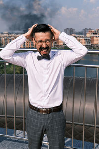 Portrait of man standing against railing in city