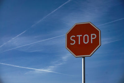 Low angle view of road sign against blue sky