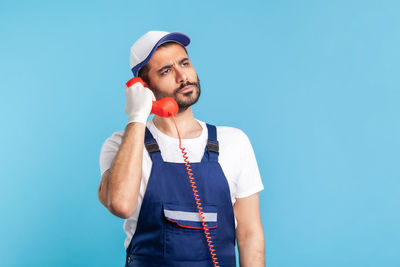 Manual worker talking on phone against colored background