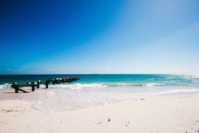 Scenic view of beach against clear blue sky