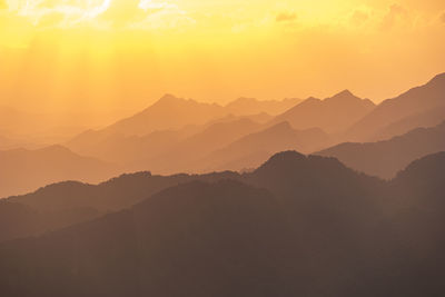 Scenic view of silhouette mountains against orange sky