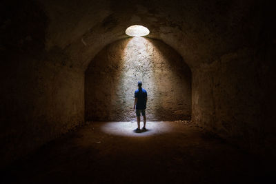 Rear view of man walking in illuminated tunnel