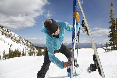 Woman waxes her skins on a backcountry tour on mount sopris, colorad