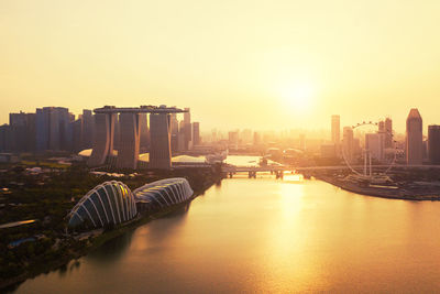 River amidst buildings in city against sky during sunset