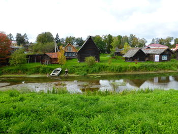 Houses on field by lake against sky