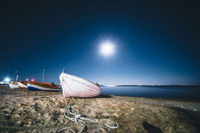 Boat moored on beach against blue sky