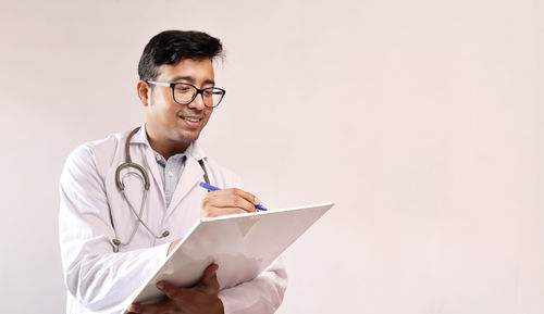 Doctor writing in paper against white background