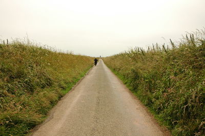 Road amidst field against clear sky