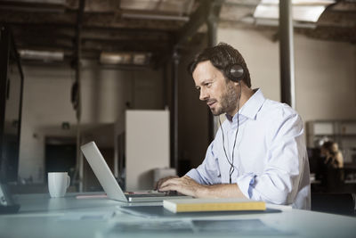 Businessman at desk with laptop and headphones