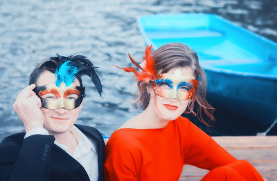 Colorful portrait of a young couple in masquerade masks. brightly dressed man and woman outdoors.