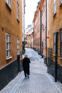 Rear view of woman on alley amidst street