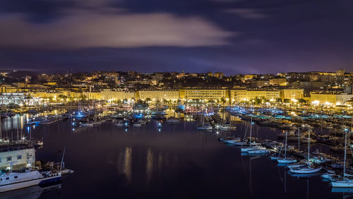 High angle view of illuminated harbor against buildings at night