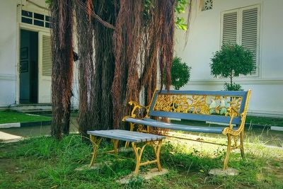 Empty bench in park against building