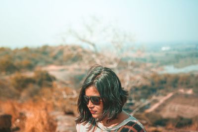 Woman wearing sunglasses standing against sky
