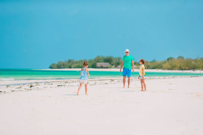 Rear view of people on beach against sky